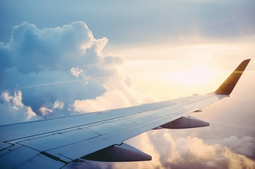 An aircraft wing above a sea of clouds at sunrise
